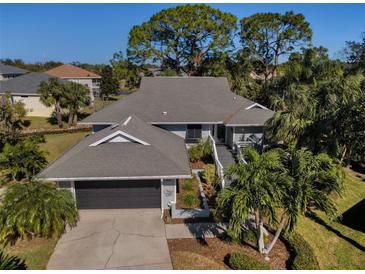 Attractive single-story home with gray roof, attached garage, and lush landscaping at 1012 Osprey Ct, Tarpon Springs, FL 34689