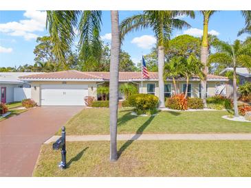 Single-story home with a landscaped yard, palm trees, and a two-car garage at 14715 Crown Dr, Largo, FL 33774