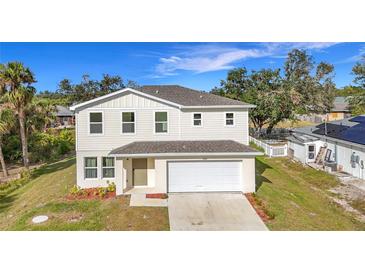 Charming two-story home with a white exterior, attached garage, and landscaped front yard at 17209 Sabrina Cir, Port Charlotte, FL 33948