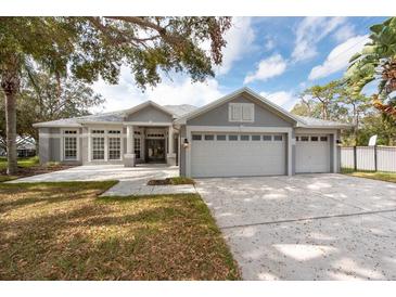 Gray house with three-car garage and landscaped lawn at 4017 Eagleflight Ln, Land O Lakes, FL 34639