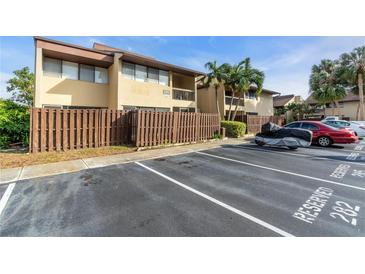 Exterior view of condo building with assigned parking spaces and surrounding landscape at 885 N Village N Dr # 204, St Petersburg, FL 33716