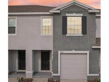 Two-story townhome with gray siding, double doors, and attached garage at 32925 Pez Landing Ln, Wesley Chapel, FL 33543