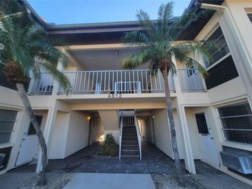 Two-story building with balcony, stairs, and tropical landscaping at 4812 Jasper Dr # 105, New Port Richey, FL 34652