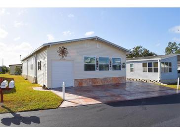 Single-wide manufactured home with attached garage and stone facade at 37526 Rio Ln, Zephyrhills, FL 33541