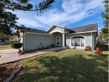 Light blue single-story home with a landscaped front yard and a welcoming walkway at 27355 Breakers Dr, Wesley Chapel, FL 33544