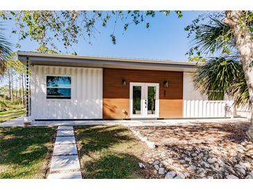 Modern container home with white and wood exterior, landscaped yard, and walkway at 489 Campbell St, Port Charlotte, FL 33953