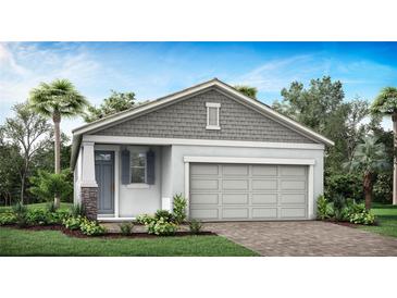 Charming single-story home with gray siding, a two-car garage, and landscaped yard at 3716 Maxwell Park Dr, Sun City Center, FL 33573