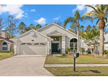 Charming single-story home with a double garage, black front door, and landscaped yard at 860 Crestridge Cir, Tarpon Springs, FL 34688