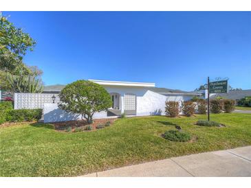 Single-story home with white exterior, landscaped yard, and a paved walkway at 1655 S Highland Ave # F227, Clearwater, FL 33756