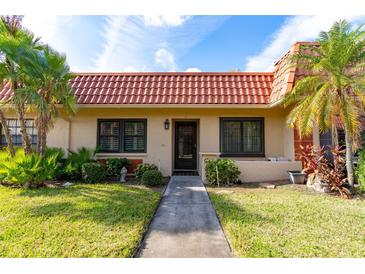 Charming one-story home with a red tile roof, lush landscaping, and a welcoming walkway at 19029 Us Highway 19 # 25D, Clearwater, FL 33764