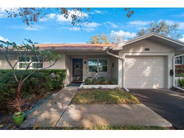 Tan house with a two-car garage and well-manicured landscaping at 2186 Marshall Dr, Dunedin, FL 34698