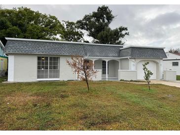 Charming single-Gathering home with a gray tiled roof, white exterior, and attached garage at 3349 Overland Dr, Holiday, FL 34691