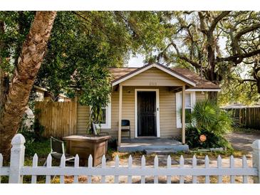 Quaint home with white picket fence, front porch, and mature trees at 8303 N Mulberry St, Tampa, FL 33604