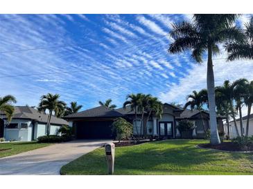 Beautiful home with a landscaped lawn, palm trees, and a two-car garage at 8384 Antwerp Cir, Port Charlotte, FL 33981