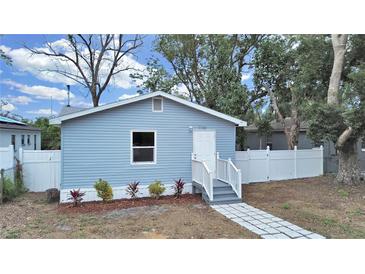 Charming light blue home with white fence and landscaping at 1708 E Poinsettia Ave, Tampa, FL 33612