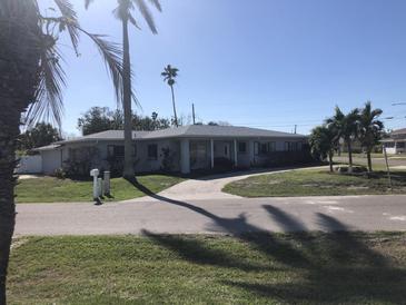 One-story home with a gray exterior, white trim, and a paved driveway at 15816 2Nd St E, Redington Beach, FL 33708