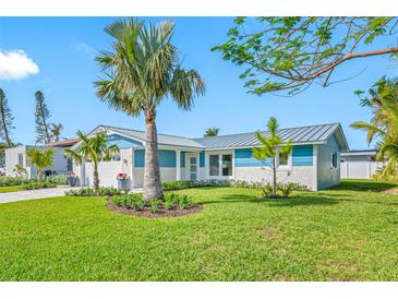 Charming blue and white home featuring a well-manicured lawn, lush landscaping, and a two-car garage at 819 59Th Ave, St Pete Beach, FL 33706