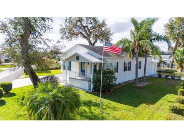 Charming single-story home with a front porch, lush landscaping, and palm trees at 37226 Lakewood Dr, Zephyrhills, FL 33542