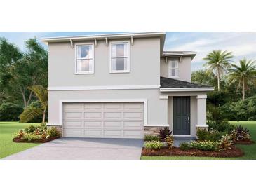 Two-story home with a two-car garage, gray siding, dark gray front door, and landscaping at 10543 Dusty Boot Rd, Land O Lakes, FL 34638