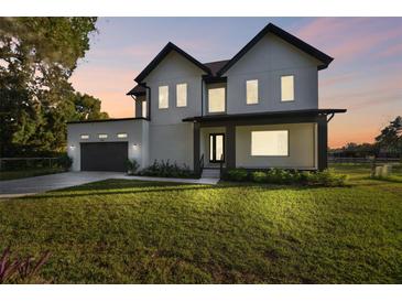 Modern two-story home with a sleek exterior, lush lawn, and attached garage at dusk at 6303 Barton Rd, Plant City, FL 33565