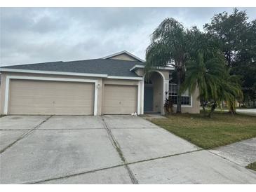 Tan two-story home with two-car garage and landscaped yard at 5239 Braddock Dr, Zephyrhills, FL 33541