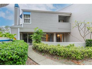 Exterior view of gray two-story condo with a walkway, patio and lush landscaping at 8737 Bardmoor Pl # 101, Seminole, FL 33777