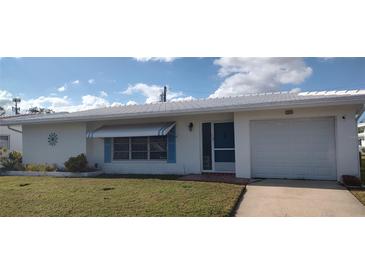 Charming single-story home featuring an attached garage, blue awning, and well-manicured lawn at 9350 Mainlands W Blvd, Pinellas Park, FL 33782