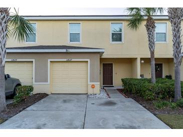Inviting townhome featuring a one-car garage, mature landscaping, and a covered front entryway at 12827 Buffalo Run Dr, Gibsonton, FL 33534