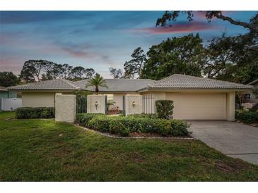 Tan one-story house with a two-car garage and manicured lawn at 970 Rolling Hills Dr, Palm Harbor, FL 34683