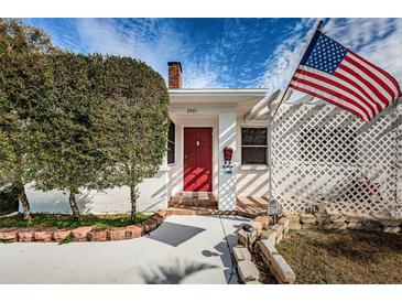 Charming home featuring a bright red front door, an American flag, and well-maintained landscaping at 3501 63Rd N St, St Petersburg, FL 33710