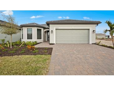 Beautiful single-Gathering home showcasing a pristine lawn, landscaped garden, and a convenient two-car garage at 17077 Moonflower Dr, Venice, FL 34293