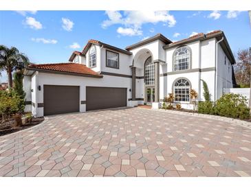 Elegant home featuring a three-car garage, beautiful stonework driveway, and a well-maintained lawn at 22847 Sonoma Ln, Lutz, FL 33549