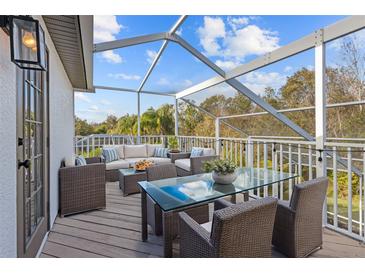 Outdoor patio featuring comfortable wicker seating, a glass table, and views of the surrounding landscape at 22847 Sonoma Ln, Lutz, FL 33549