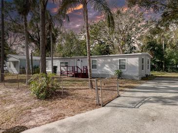 Single-wide mobile home with a small deck and fenced yard at 4110 Wedgemere Dr, Tampa, FL 33610