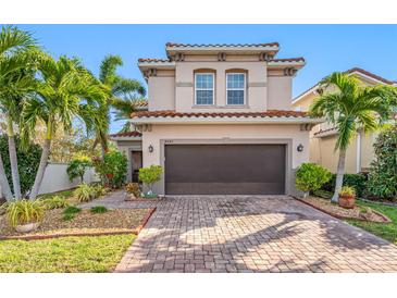 Two-story house with brown garage door, landscaping, and brick paver driveway at 4943 Grand Oak Cir, Madeira Beach, FL 33708