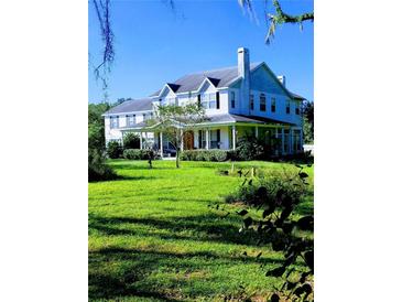 Two-story home with wrap-around porch and large green lawn at 13621 Mcintosh Rd, Thonotosassa, FL 33592