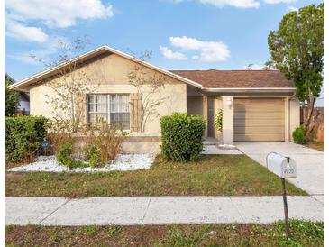 Tan house with brown roof, landscaping, and a two-car garage at 2020 San Sebastian S Way, Clearwater, FL 33763