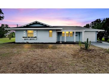 Light blue house with a white garage door and landscaped yard at 1201 Harkness Way, Sun City Center, FL 33573