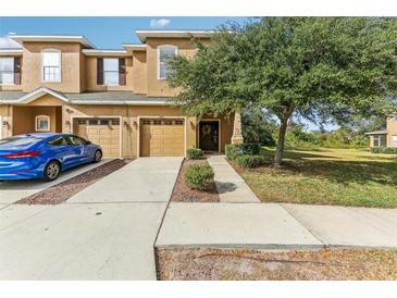 Tan two-story townhome with two-car garage and landscaping at 12821 Avelar Manor Pl, Riverview, FL 33578