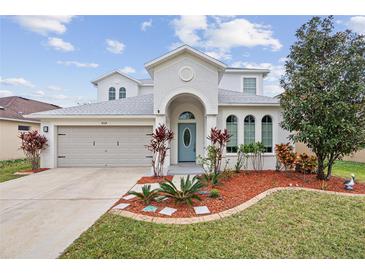 Charming two-story home with a well-manicured lawn, arched entrance, and attached two-car garage at 4104 Warwick Hills Dr, Wesley Chapel, FL 33543