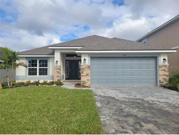 One-story house with gray siding, stone accents, and a two-car garage at 36141 Welsh Glade Rd, Dade City, FL 33525