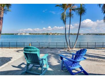Relaxing waterfront view with two chairs, palm trees, and peaceful water at 16101 6Th E St, Redington Beach, FL 33708