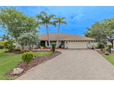 Charming single-story home featuring mature landscaping, a brick driveway, and an attached two-car garage at 1000 Chillum Ct, Safety Harbor, FL 34695
