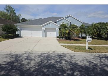 Two-story house with light blue exterior, two-car garage, and palm trees at 5125 Silver Charm Ter, Wesley Chapel, FL 33544