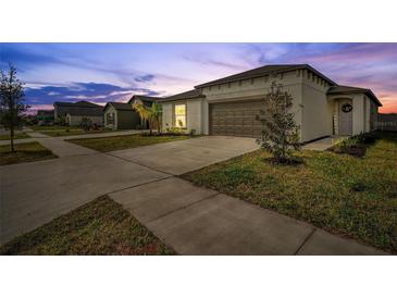 One-story house with attached garage and landscaped lawn at 5493 Blue Azure Dr, Wimauma, FL 33598