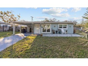Light blue house with a covered patio and well-maintained lawn at 1890 San Mateo Dr, Dunedin, FL 34698