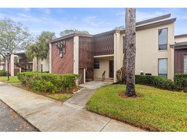 Exterior view of condo building with landscaped grounds at 1200 Tarpon Woods Blvd # R7, Palm Harbor, FL 34685