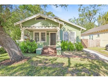 Charming craftsman home with a green exterior, porch, and well-maintained lawn at 213 W Cayuga St, Tampa, FL 33603