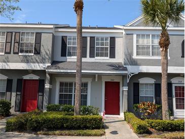 Charming townhome with vibrant red door, lush landscaping and tropical palm trees, offers inviting curb appeal at 262 Countryside Key Blvd, Oldsmar, FL 34677