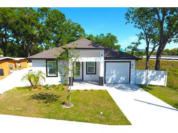 Charming single-story home with white exterior, manicured lawn, and attached garage at 408 E Hanlon St, Tampa, FL 33604